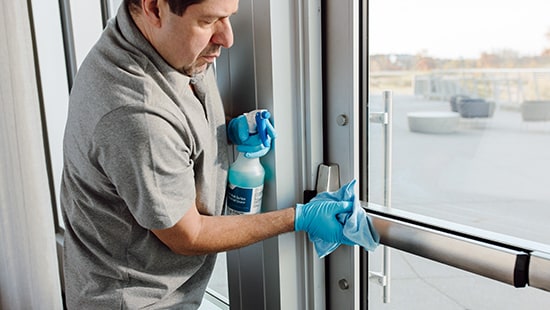 BSC Cleaner using Rapid Multi Surface Disinfectant Cleaner spray bottle and blue microfiber use on exterior glass door high touch point