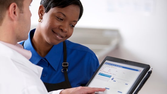 An Ecolab specialist performing a Value Visit by showing an employee information on an iPad computer chart.