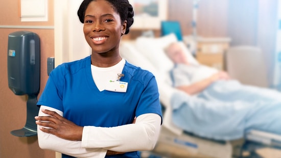 Ecolab healthcare professional working in a hospital room next to a Hand Hygiene foam soap dispenser.