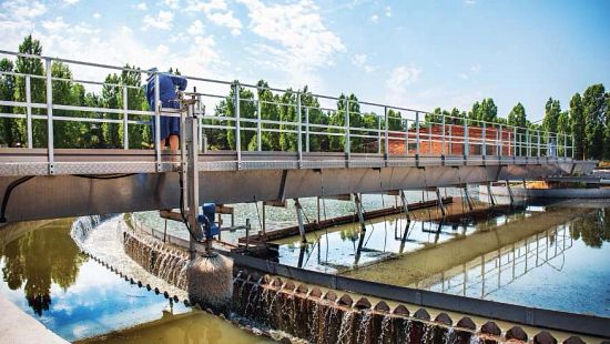 Worker atop a bridge at facility for urban wastewater, the treatment of which is an Ecolab solution to support our customers’ businesses.